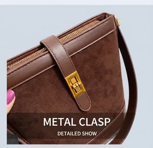 Detail of the vintage gold hardware lock and suede texture on a brown bucket bag