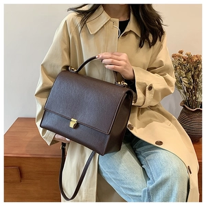 Detail shot of vintage dark brown pebble leather crossbody bag with golden metal buckle