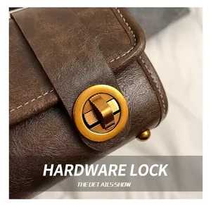 Details vom goldenen Drehverschluss an brauner Ledertasche mit Kontrastnähten