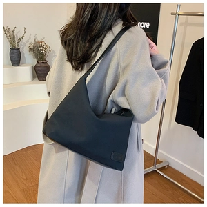 Détail d'un sac hobo en nylon noir minimaliste porté de dos par un mannequin