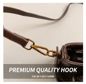 Detailed close-up of golden metal hooks and leather strap on a brown bucket bag