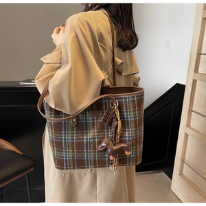 Detail of checkered tote bag featuring a leather dachshund charm and chocolate block pendant
