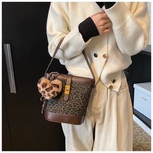 Detail of leopard print bucket bag with gold clasp and heart plush charm on a model