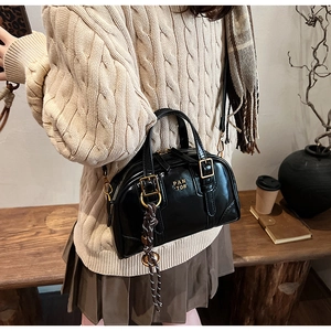 Detail of a black leather boston bag with gold PAN TOR lettering and vintage hardware