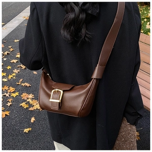 Dettaglio di una borsa hobo in pelle marrone con motivo litchi e fibbia dorata in strada
