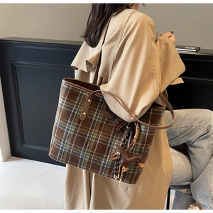 Detail of wool blend plaid tote bag with brown leather handles and cute dog charm