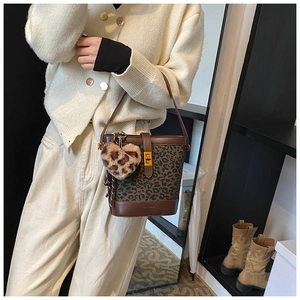 Detail of leopard print bucket bag with brown leather trim and a plush heart charm