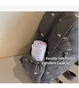 Detailed side view of quilted grey backpack with bow embroidery and umbrella in pocket