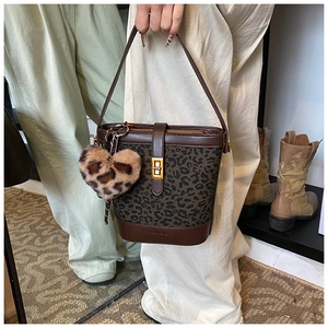 Detail of leopard bucket bag with gold clasp, heart charm and brown leather trim