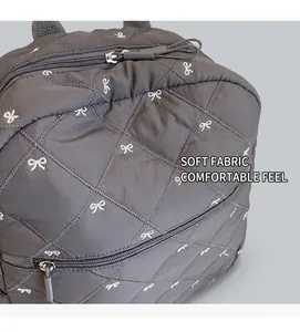 Detail of grey quilted nylon backpack with white butterfly embroidery and zipper cord