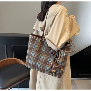 Detail of plaid tote bag with brown leather handles and cute dachshund charm accessory