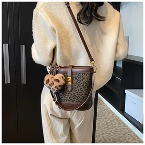 Detail of a brown leopard print bucket bag with metal turn-lock and plush heart charm