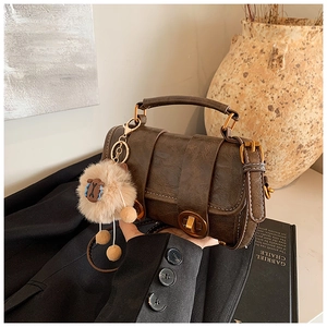 Detail der braunen Vintage-Lederhandtasche mit Goldbeschlägen und Schaf-Anhänger