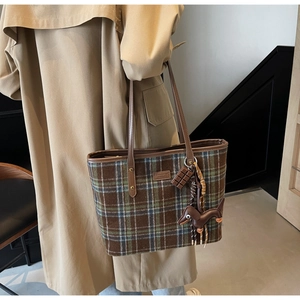 Detail of checkered tote bag featuring a leather dachshund charm and teddy bear logo
