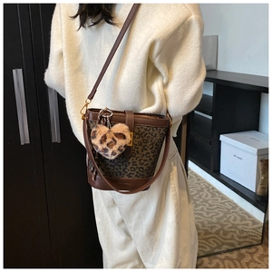 Close-up of leopard print bucket bag with plush heart charm on casual outfit