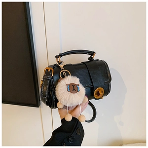 Detailansicht schwarze Lederhandtasche mit goldenem Schloss und Plüschschaf-Anhänger