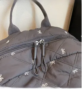 Detailed close-up of smooth dual metal zippers on a dark grey quilted backpack