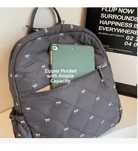 Detailed view of the front zipper pocket holding a tablet in a quilted bow backpack