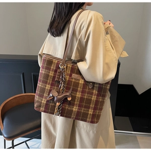 Detailed view of checkered tote bag featuring a leather strap and dachshund charm