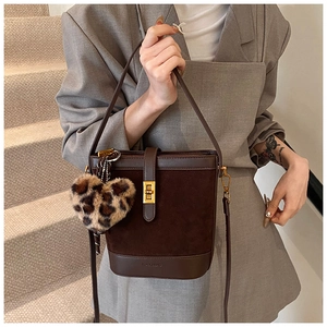 Close-up of brown bucket bag with gold clasp and leopard print heart plush charm