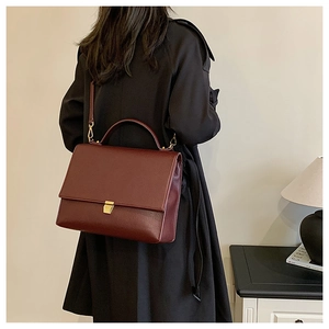 Close-up of vintage dark burgundy leather crossbody bag with metallic lock detail