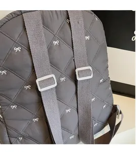Detailed back view of grey quilted backpack with bow embroidery and adjustable straps