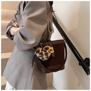 Detail of a brown bucket bag with golden buckle and a leopard print heart charm