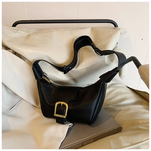 Dettaglio borsa a mezzaluna in pelle martellata nera con fibbia dorata su seduta color crema