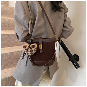 Detail view of coffee brown bucket bag with leopard heart charm and gold buckle