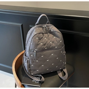 Détail du sac à dos matelassé gris foncé avec broderie de nœuds blancs et poche latérale