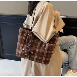 Close-up of brown plaid tote bag with leather straps and dachshund charm detail