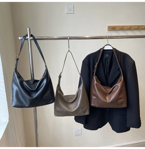 Tre borse hobo retrò in nero, marrone e grigio esposte in una boutique elegante