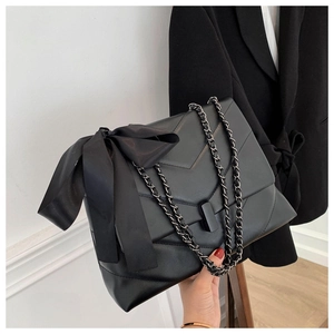 Détail du sac bandoulière matelassé noir avec un grand nœud en soie décoratif