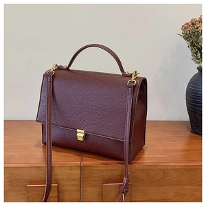 Detailed view of burgundy leather handbag with premium gold square lock and handle