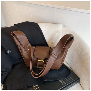 Dettaglio borsa a mezzaluna in pelle marrone con grande fibbia dorata e tracolla larga