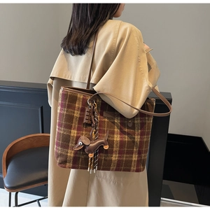 Plaid tote bag with dachshund charm and chocolate detail worn by a model in a room