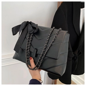 Détail du sac cabas matelassé noir avec grand nœud en satin et bandoulière chaîne