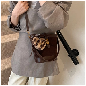 Detail of dark brown bucket bag featuring matte leather texture and leopard heart charm