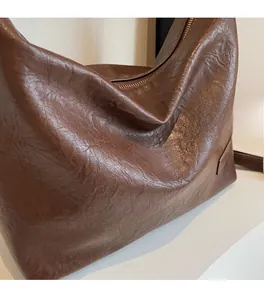 Dettaglio della consistenza della pelle marrone scuro e delle pieghe morbide di una grande borsa