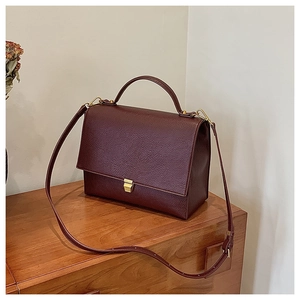 Detailed close-up of dark burgundy litchi grain leather texture and gold metal clasp