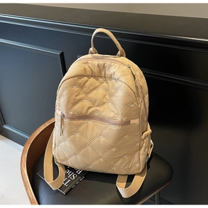 Vue détaillée du sac à dos matelassé beige avec petits motifs de nœuds papillons brodés