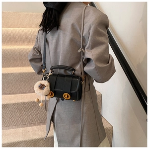 Detail der schwarzen Boston Bag aus Leder mit goldenen Drehverschlüssen und Plüschanhänger