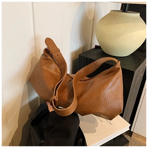 Gros plan du sac demi-lune marron vintage avec bandoulière réglable sous une lumière douce