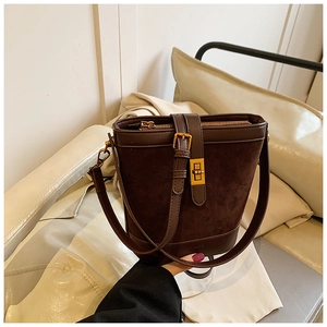 Detail of dark brown bucket bag featuring gold twist lock and smooth leather splicing
