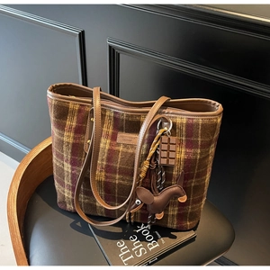 Detail of tweed tote bag with leather straps and bear charms on a leather seat