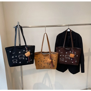 Detailed view of three suede tote bags with cute bear graphics and plush bear charms