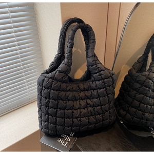 Detailed view of black quilted tote bag texture with plush puffy padding and seamless design