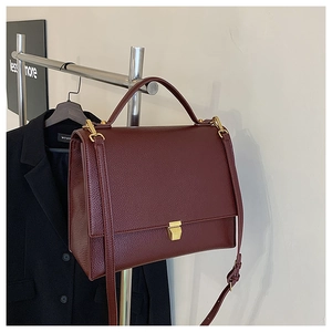 Detailed macro view of the wine red lychee pattern leather bag with gold buckle