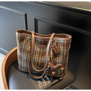 Close-up of checkered tote bag with teddy bear logo and cute dachshund charm on chair