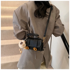 Detail der schwarzen Vintage-Tasche mit goldenen Schnallen und süßem Bärenanhänger